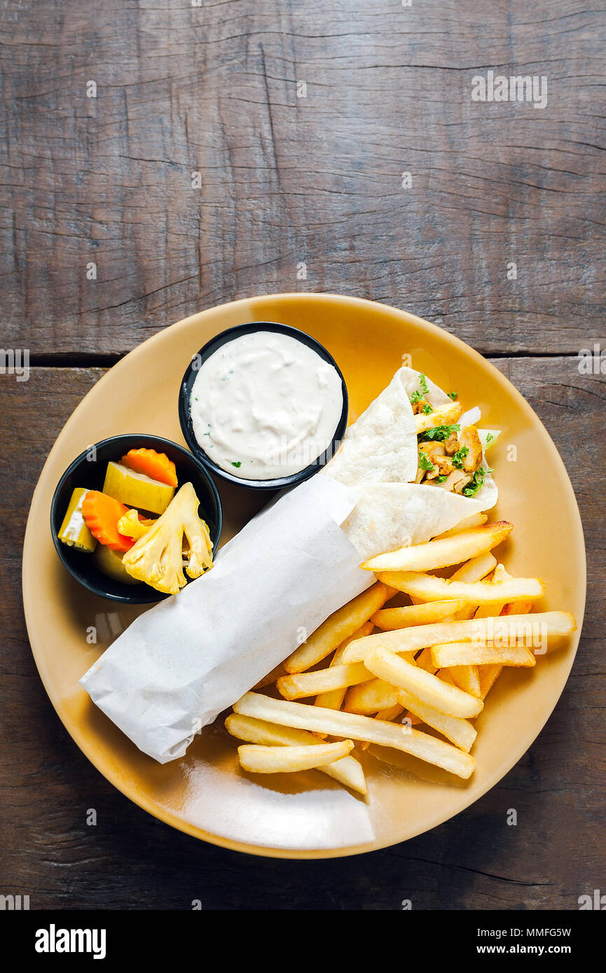 Griechische Gyros in pita Brot umwickelt. Mit Pommes frites serviert auf einem hölzernen Hintergrund Stockfoto