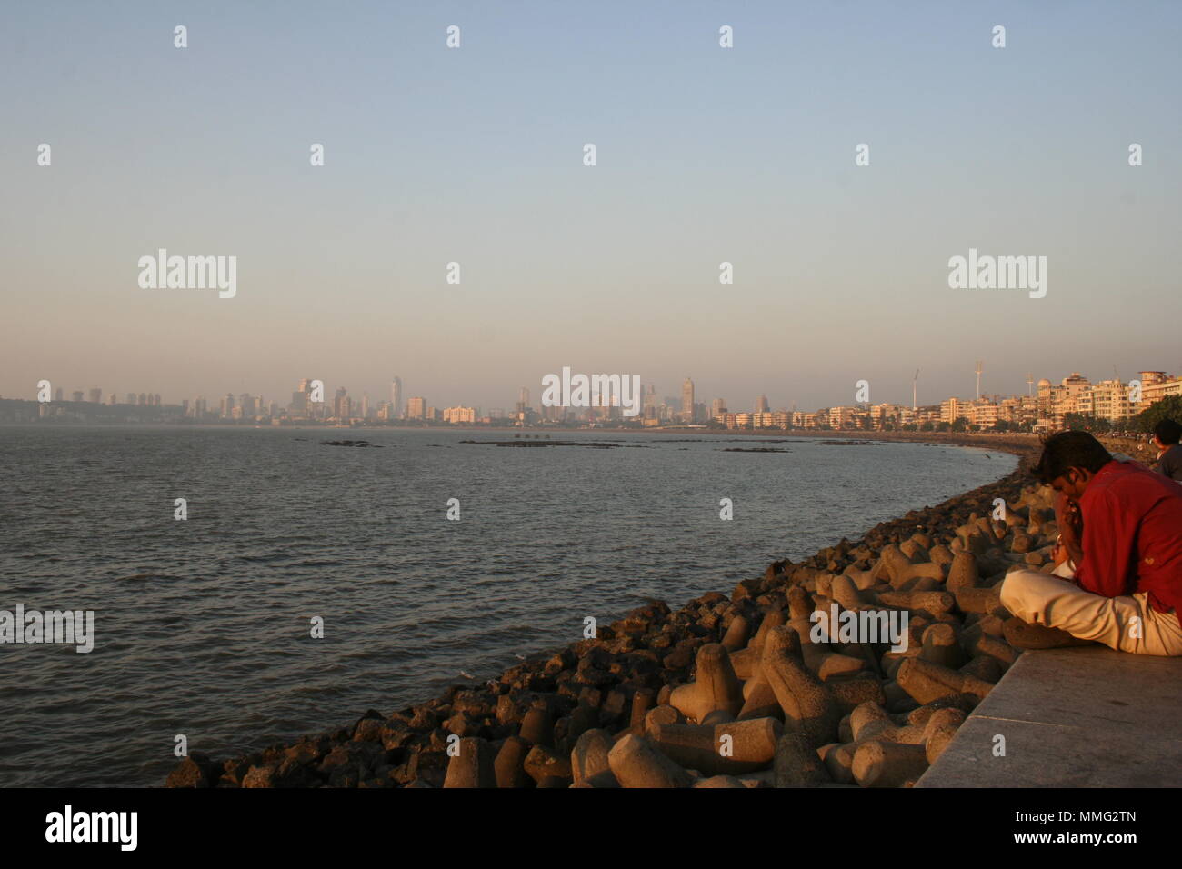 Indische Mann sitzt am Meer am Marine Drive, Mumbai, Indien Stockfoto