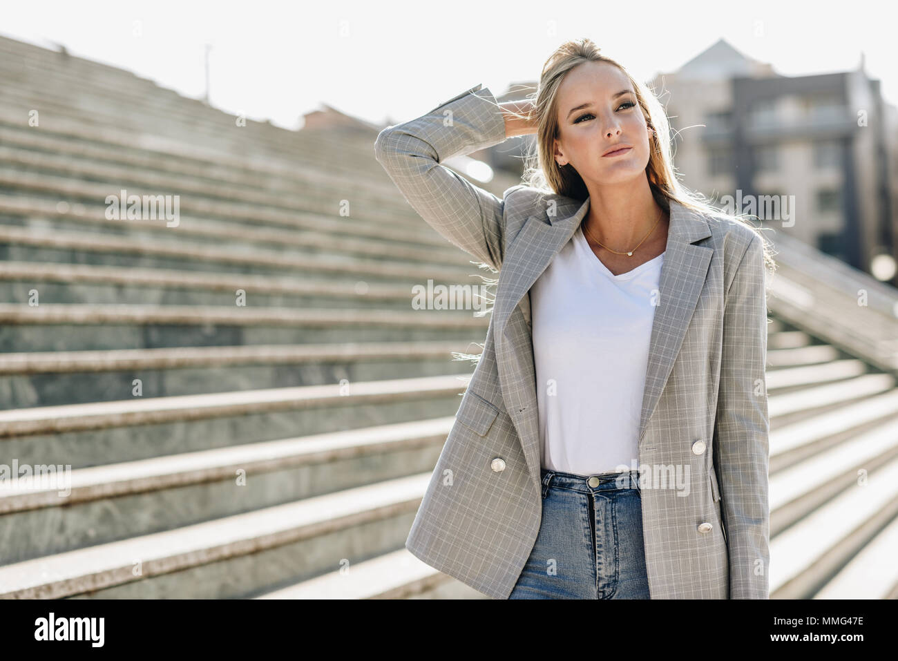 Schönen jungen kaukasischen Frau im städtischen Hintergrund. Blonde Mädchen legere  Kleidung auf der Straße. Weibchen mit elegante Jacke und blaue Jeans standi  Stockfotografie - Alamy