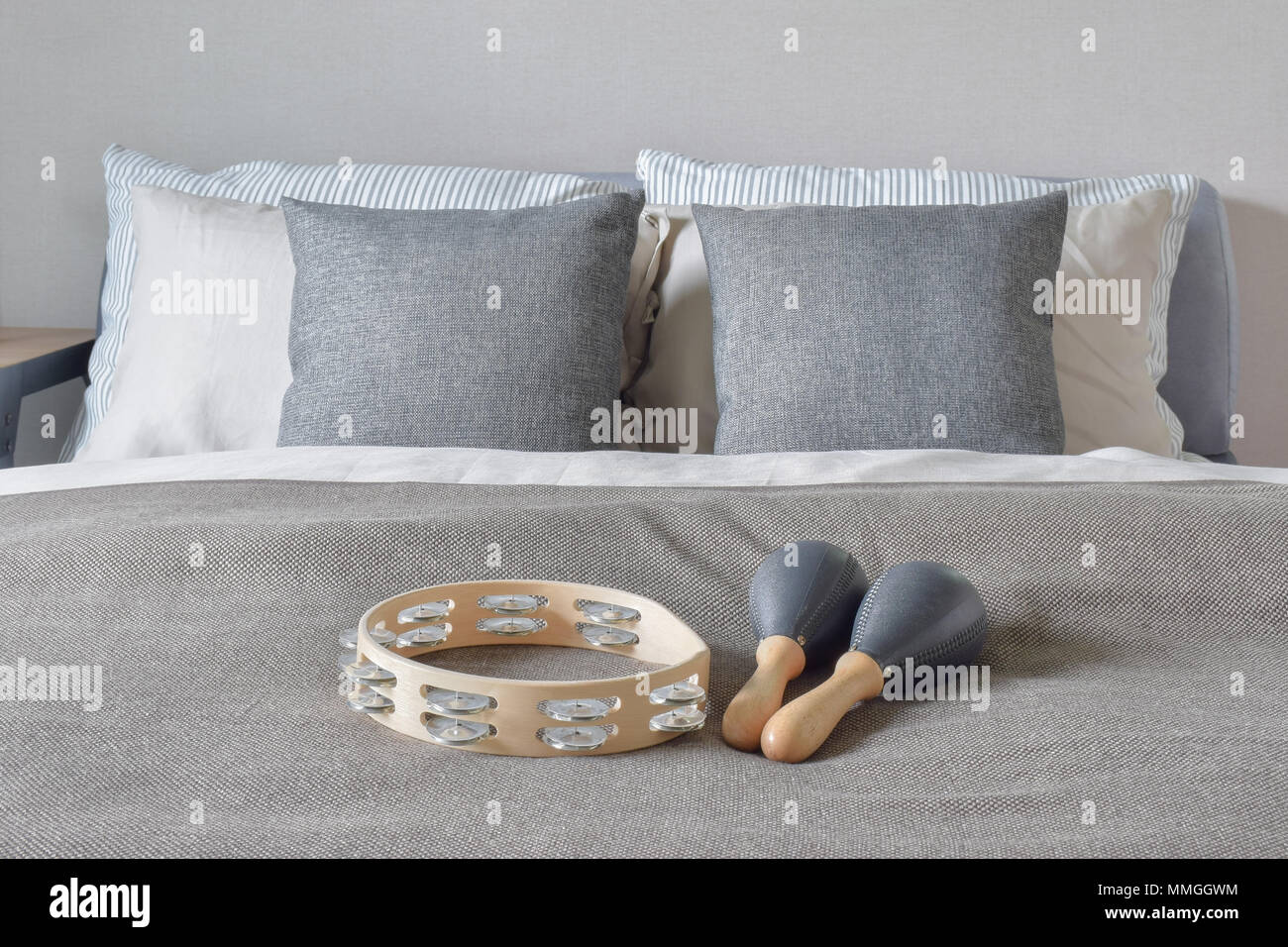 Tamburin und Maracas Einstellung auf Bett mit grauen Farbtönen Betten im Schlafzimmer Stockfoto