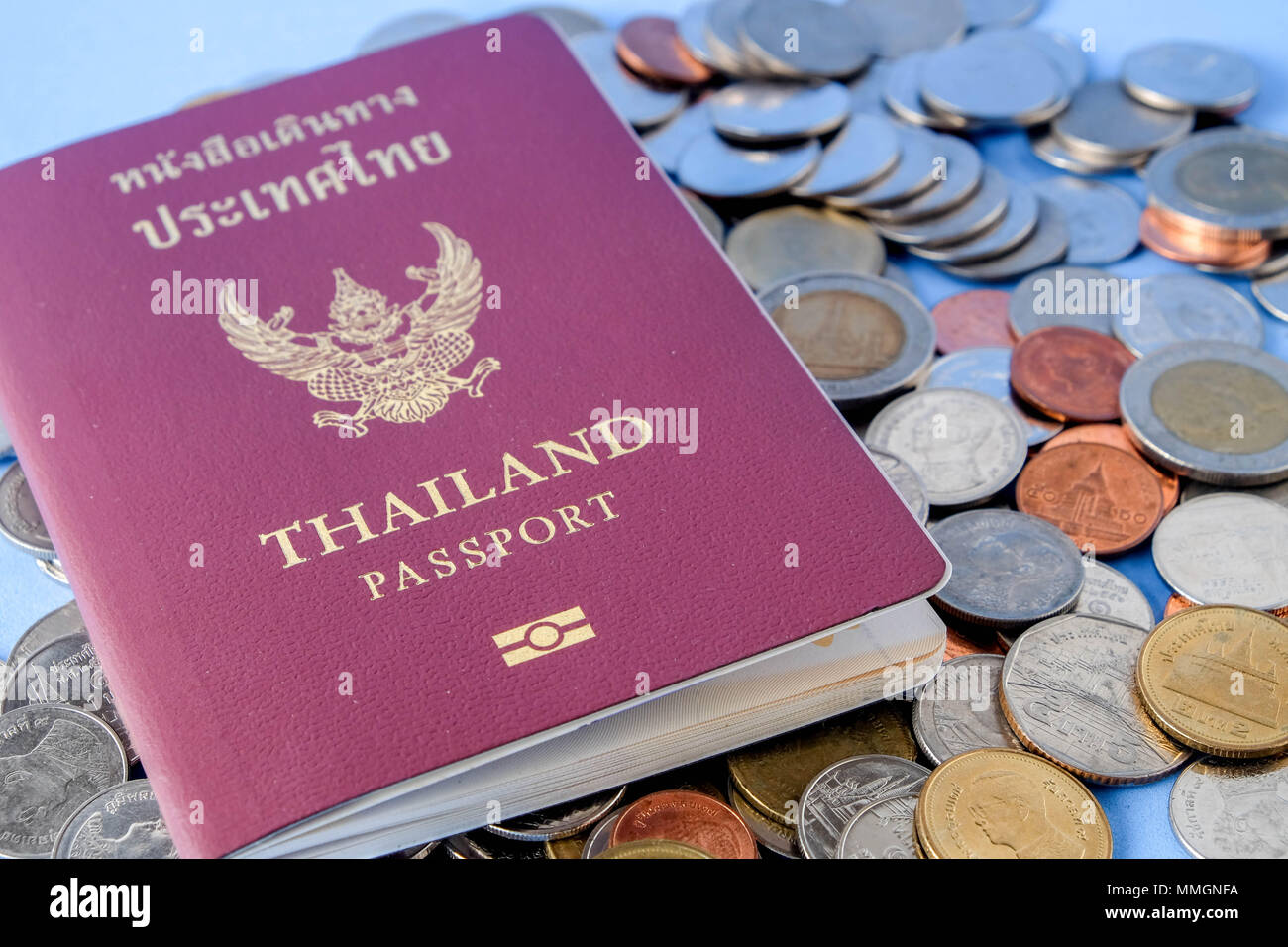 Thailand Reisepass braun umfassen und Geld Münze auf blauem Papier Hintergrund für Reisen Stockfoto