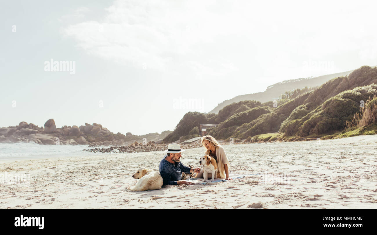 Senior paar Erholung am Strand Sand mit ihren Hunden. Reifer Mann und Frau mit Hunden am Ufer am Morgen. Stockfoto