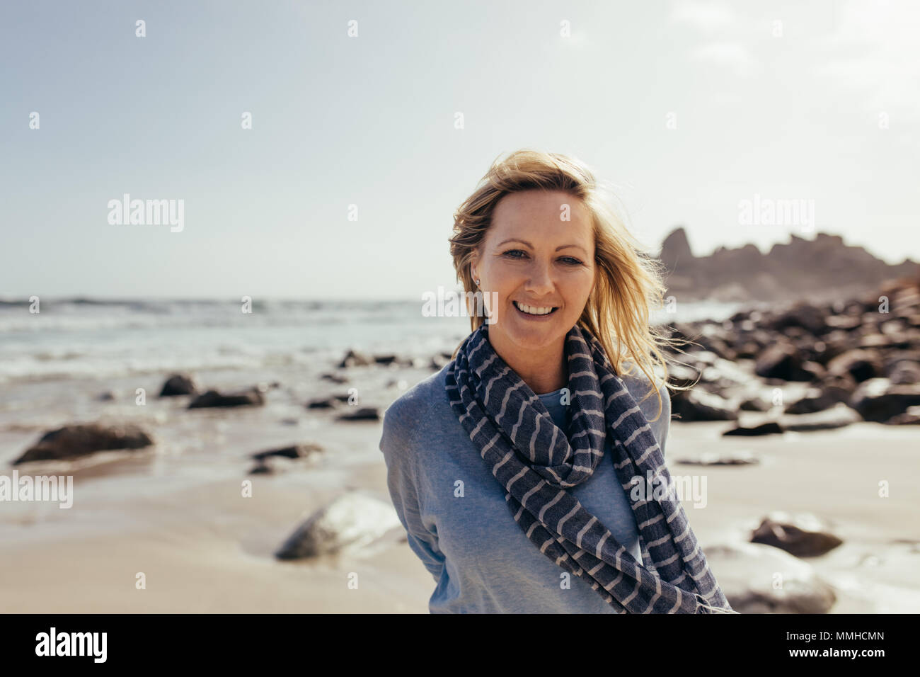 Portrait von Schöne ältere Frau, die am Strand und lächelnd. Positive reife weibliche am Ufer des Meeres. Stockfoto