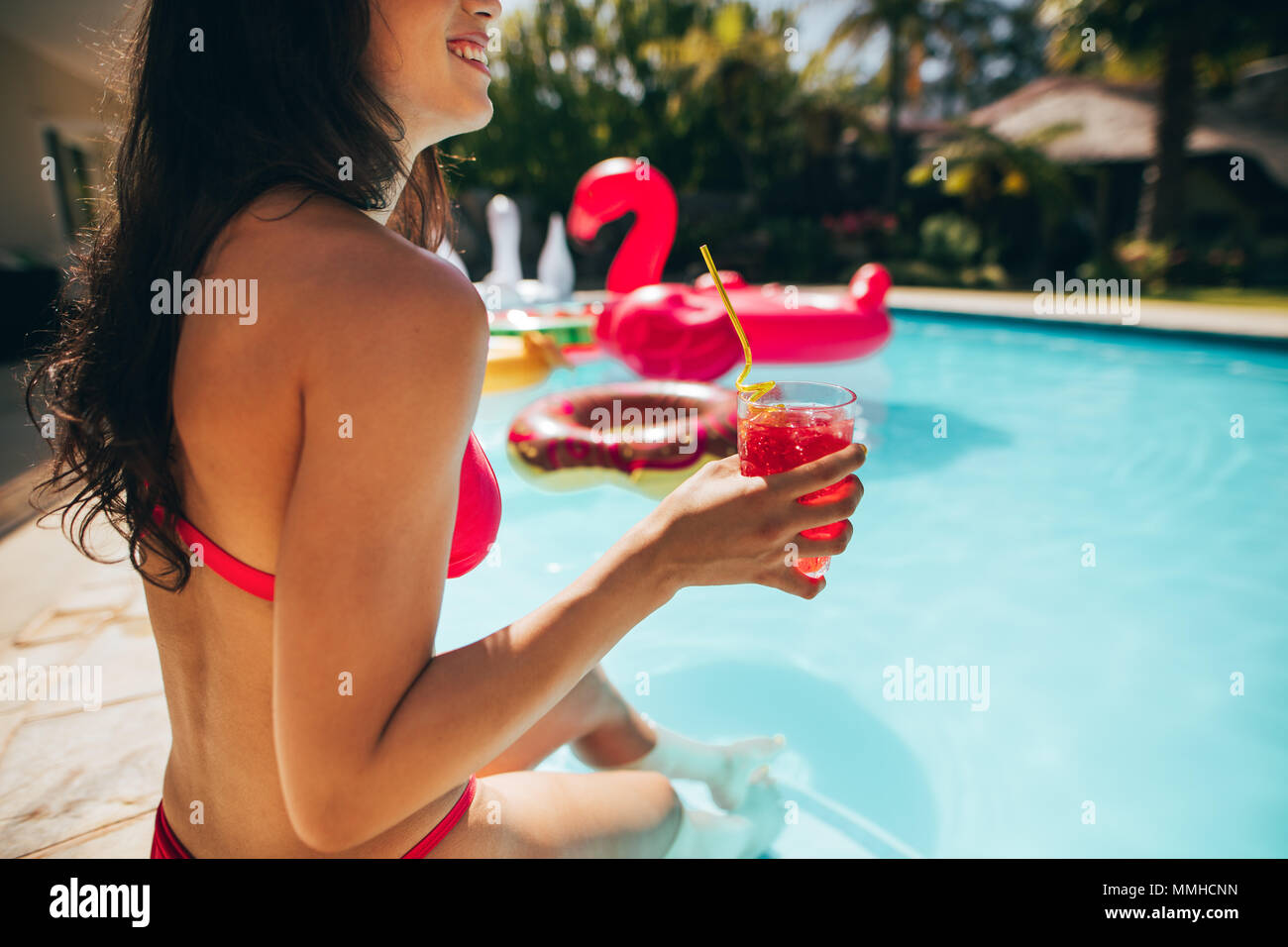 Nahaufnahme von Frau im Bikini am Pool mit einem Cocktail in der Hand. Weibliche entspannen am Pool im Sommer. Stockfoto