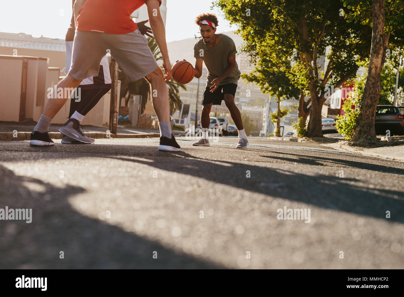 Männer spielen Basketball Spiel an einem sonnigen Tag auf einer leeren Straße. Männer üben Basketball Dribblings auf der Straße. Stockfoto