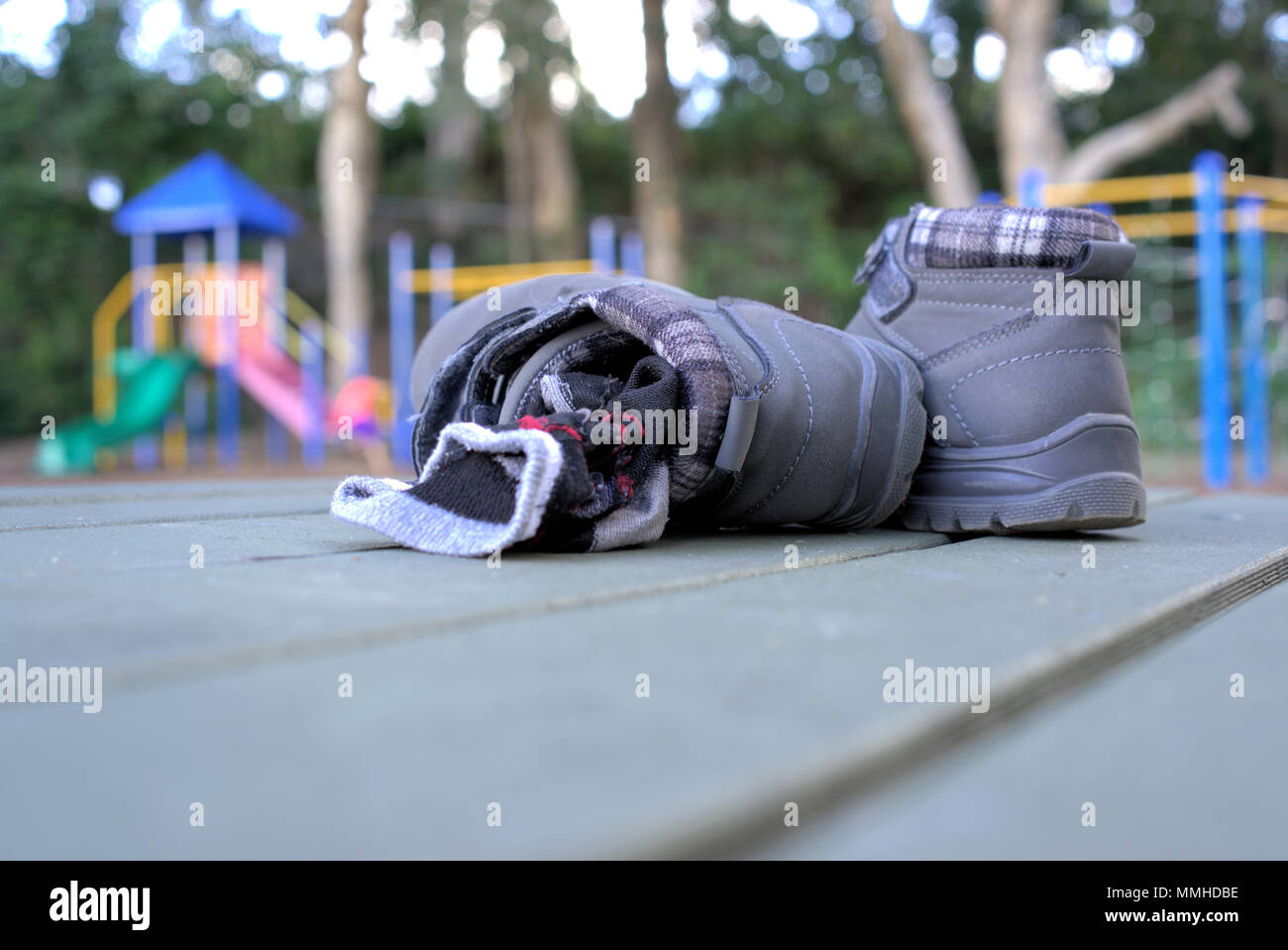 Kid entfernt Paar Stiefel und Socken mit Kindern spielen auf Fahrten im Park im Australischen Vorstadt. Stockfoto