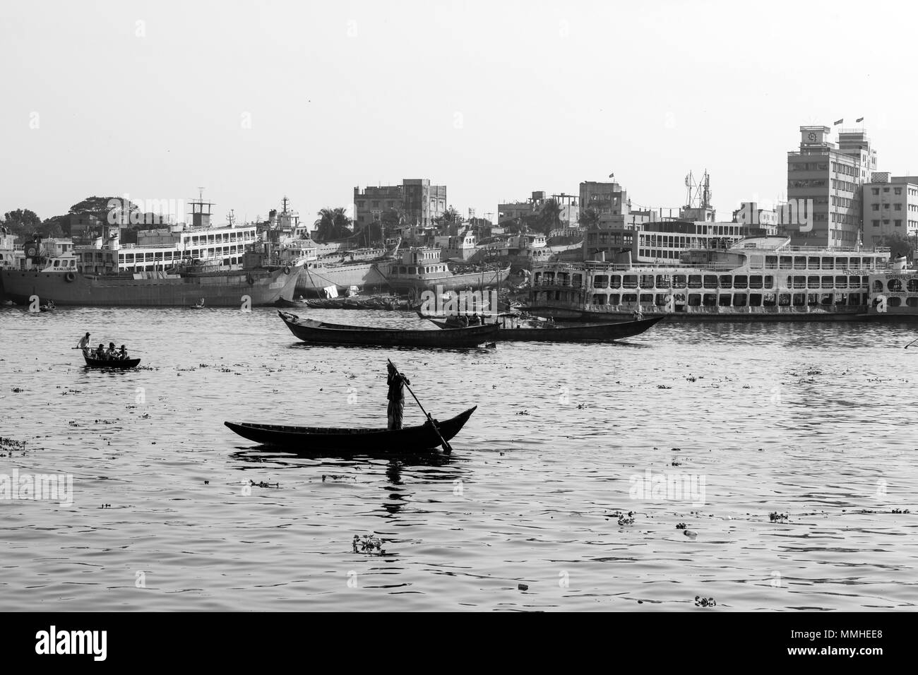 Dhaka, Bangladesh, 24. Februar 2017: rudern Boote auf dem Fluss Buriganga in Dhaka, Bangladesch und im Hintergrund die alte Werft Stockfoto