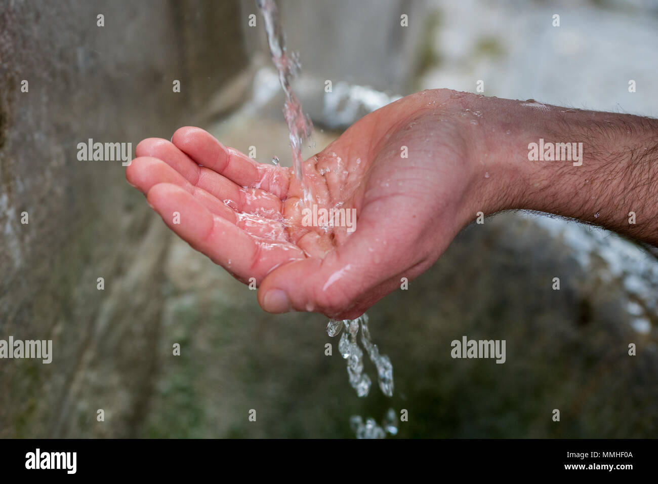 Männliche hand Sammeln von Wasser aus einem Brunnen. Frisches Wasser aus einem Teich Stockfoto
