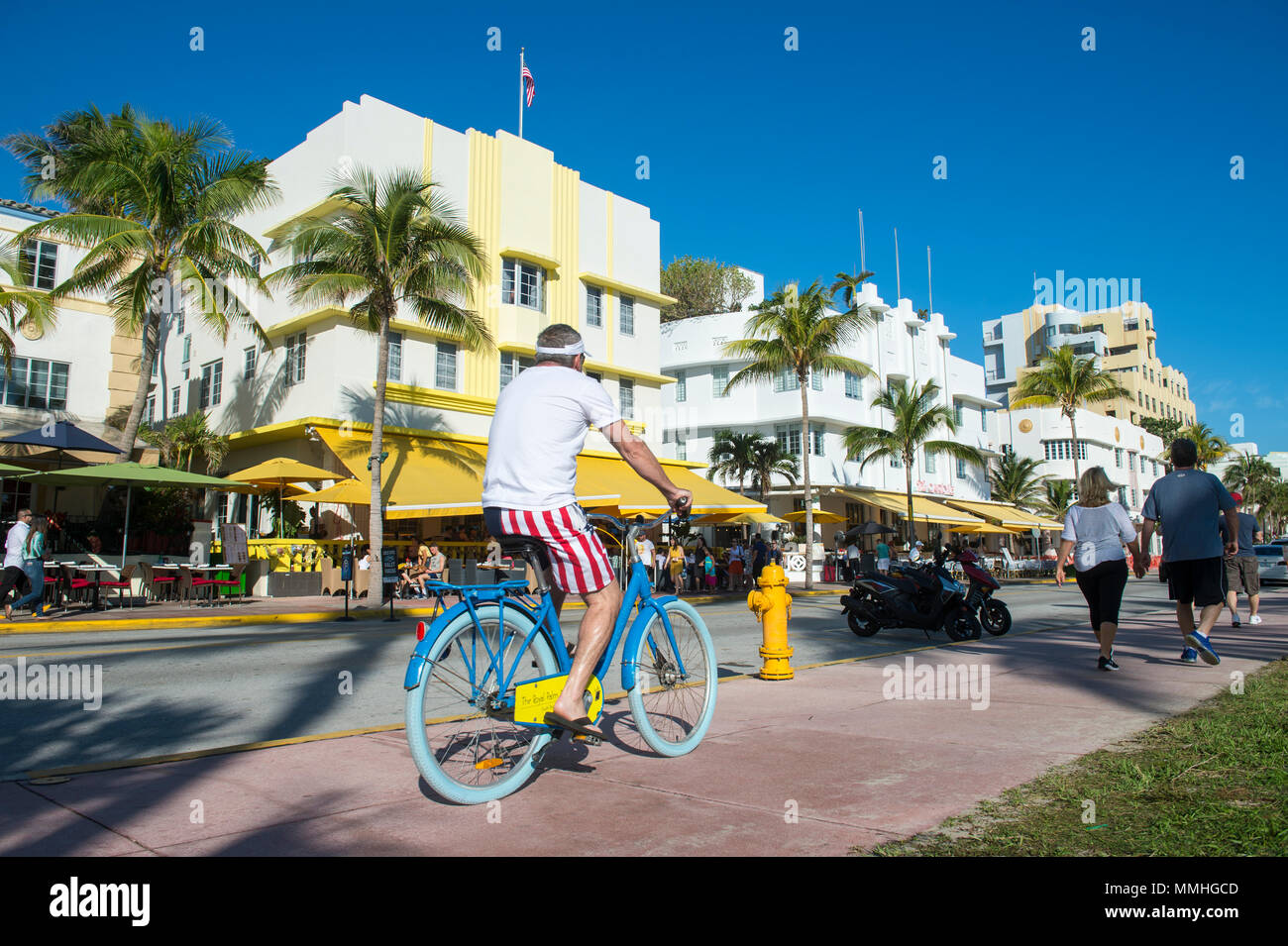 MIAMI - Dezember 29, 2017: Besucher gehen mit ihren Fahrrädern hinter der berühmten Art déco-Architektur des Ocean Drive. Stockfoto