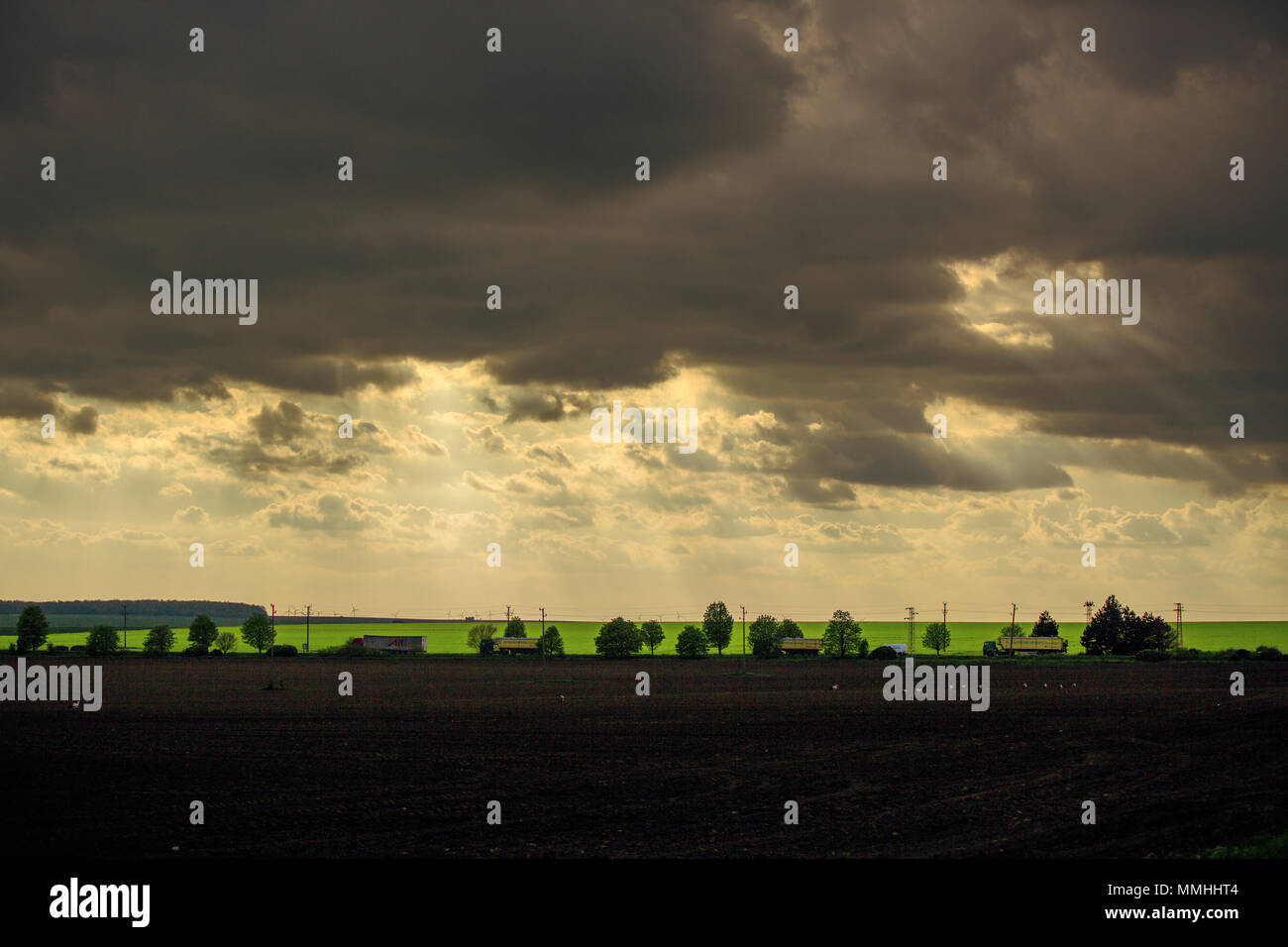 Sonnenuntergang mit dramatischen cloudscape über landwirtschaftliche auf Feld und Straße mit Autos und Lkws. Stockfoto