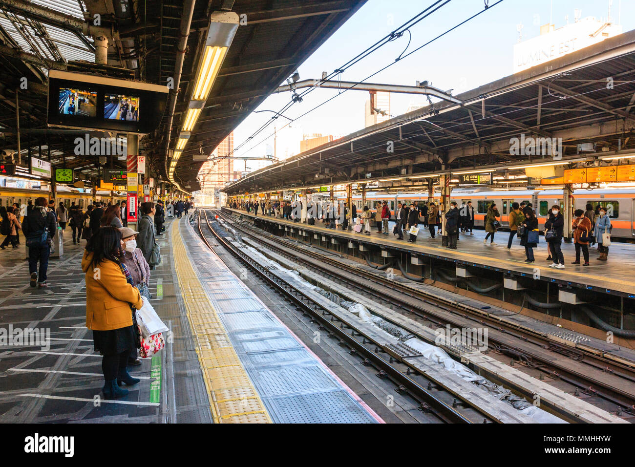 Tokyo, Shinjuku Station, der Yamanote Linie. Blick entlang der Plattform und Tracks. Viele Menschen warten auf der Plattform, im Winter. Tagsüber. Stockfoto