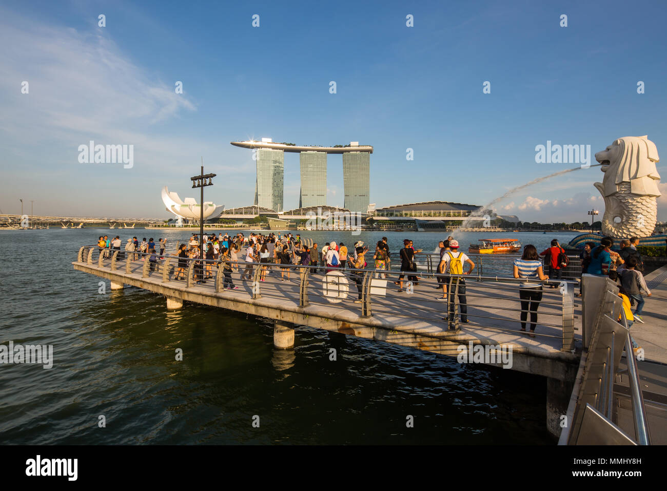 Touristen, die am Abend in Singapur den Halbfisch und den Halblion des berühmten Merlion auschecken. Stockfoto