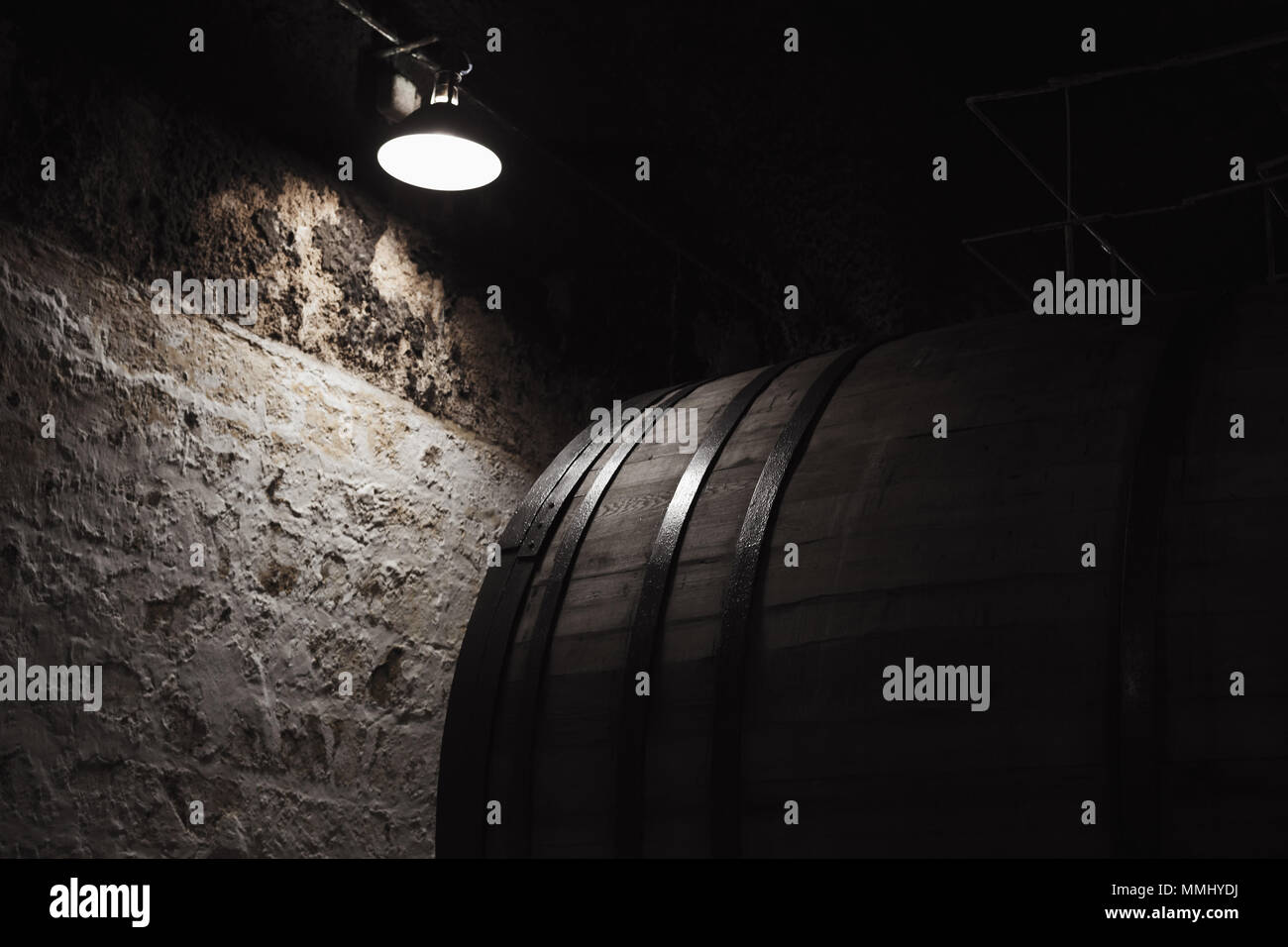 Alten Holzfass unter elektrische Lampe in dunklen Weingut, bis schließen Foto mit selektiven Fokus Stockfoto