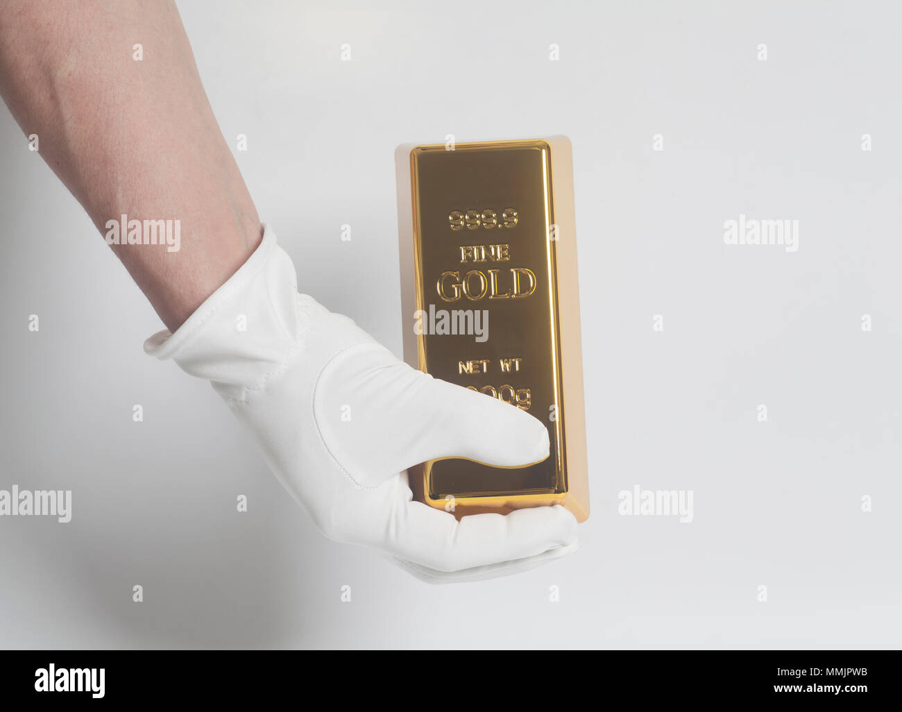 Männer Hand in weißen Handschuhen mit einem Goldbarren auf weißem Hintergrund Stockfoto