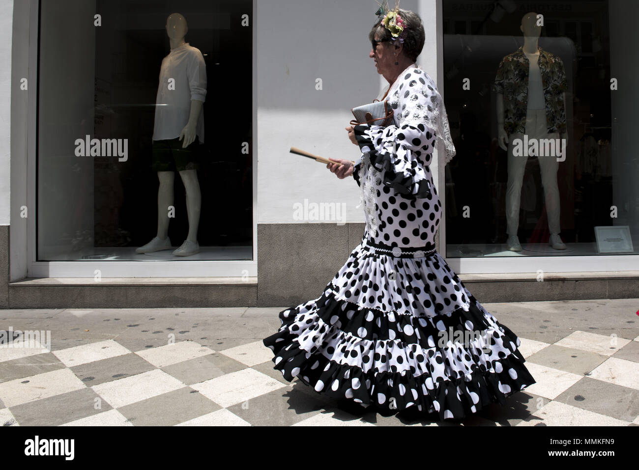 Granada, Granada, Spanien. 12. Mai 2018. Eine Frau tragen typische Kleid Pass vor einem Schaufenster während der Prozession von El Rocio. Die "Romeria del Rocio'' ist eines der beliebtesten Feste in Andalusien, Tausende von Pilgern in Almonte Dorf gehen (Huelva) anzubeten, Virgen del Rocio. Credit: Carlos Gil/SOPA Images/ZUMA Draht/Alamy leben Nachrichten Stockfoto