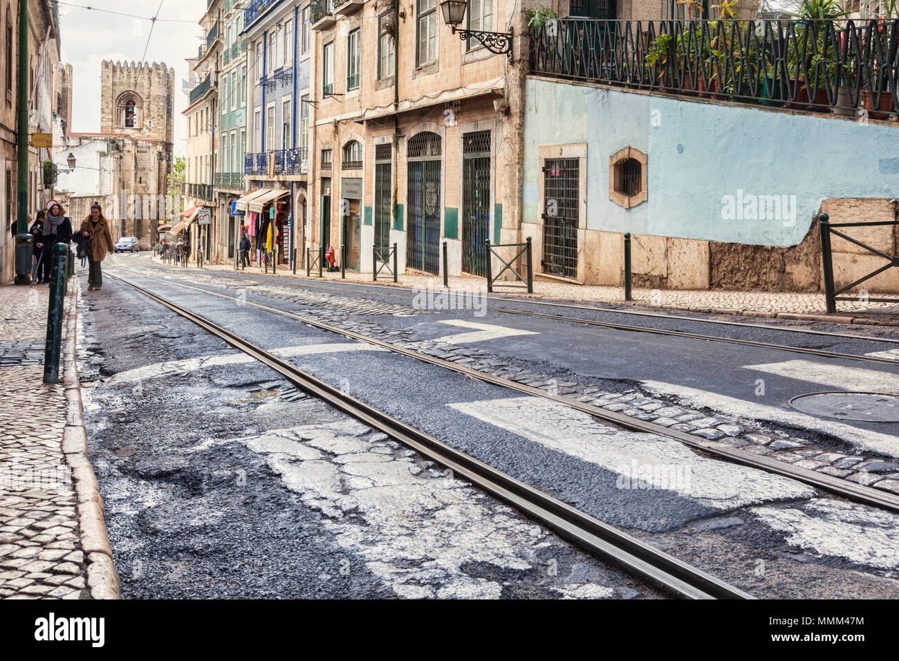 1. März 2018: Lissabon Portugal - Straße mit Straßenbahnschienen in schlechtem Zustand in der Alfama. Kathedrale von Lissabon im Hintergrund. Stockfoto