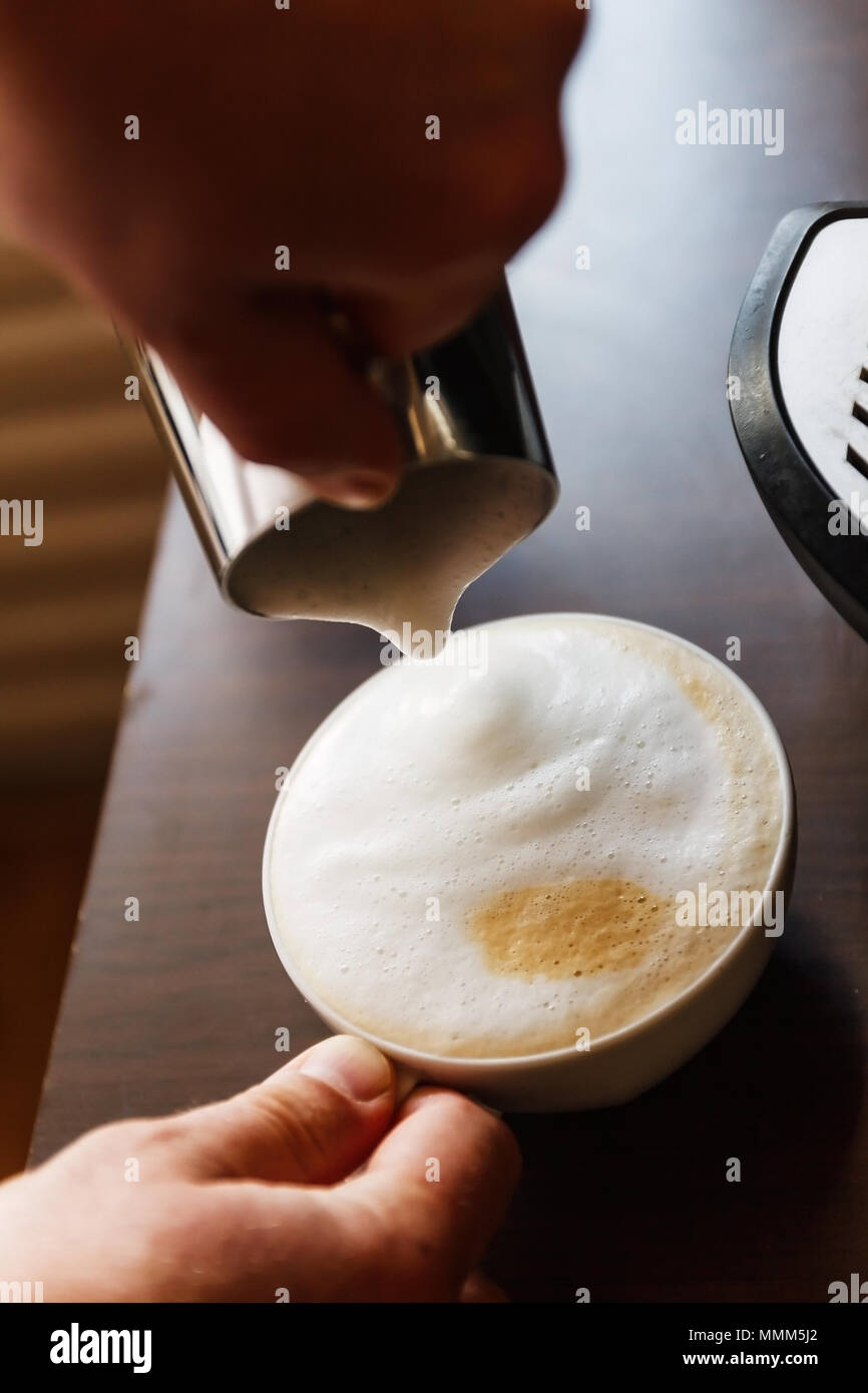 Man gießt in eine Tasse Kaffee mit Milch. Stockfoto