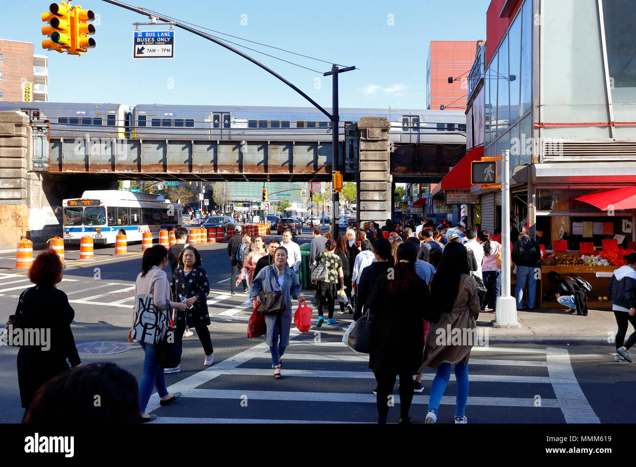 Menschen, die die Straße in Downtown Flushing in Queens, New York, NY überqueren. Im Hintergrund, Zug- und Busverkehr, Mai 2018. 法拉盛, 法拉盛華埠, 華裔美國人, 紐約 Stockfoto