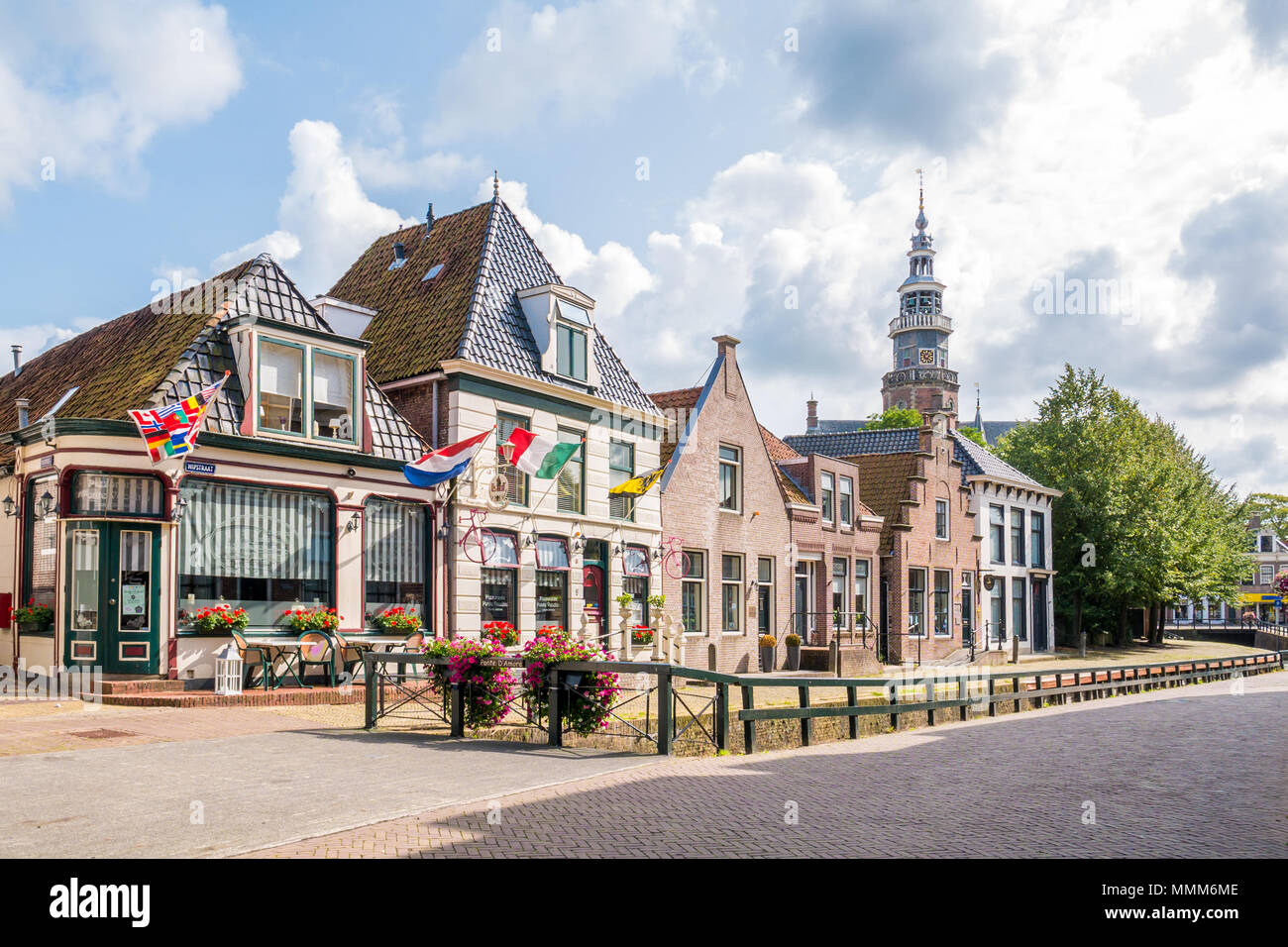 Die Fassaden der historischen Häusern und Cafés am Kai und Turm des Rathauses in der Altstadt von Bolsward, Friesland, Niederlande Stockfoto