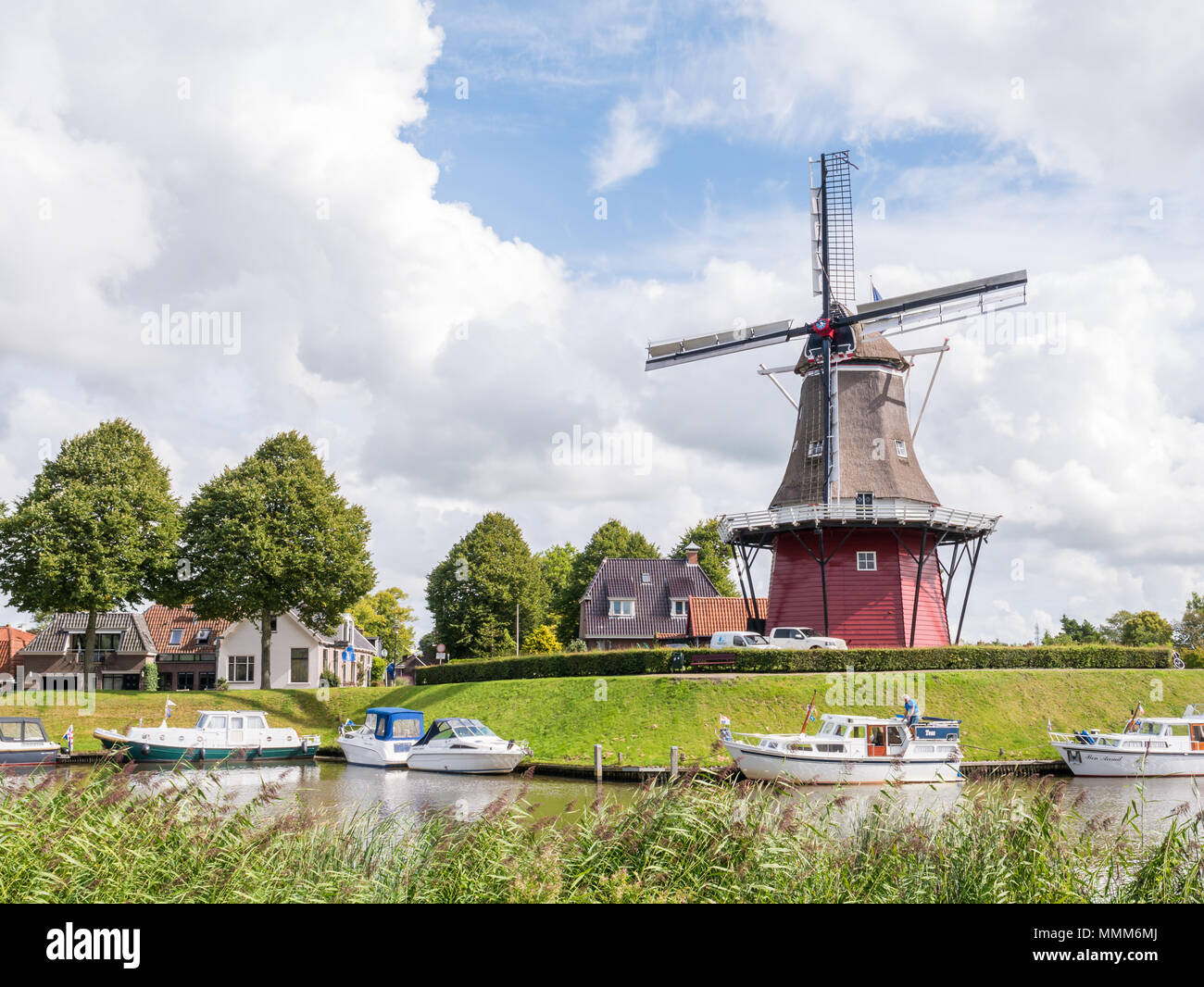 Motorboote auf den Kanal und die Windmühle auf Befestigungsanlagen der historischen Festungsstadt Dokkum, Friesland, Niederlande Stockfoto