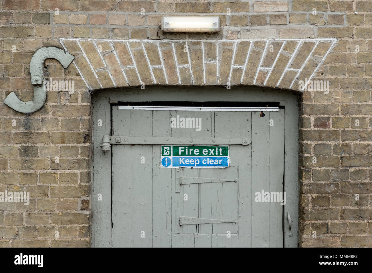 Detaillierte Bild einer Notausgangstür und Zeichen zu einem alten Holz Tür an der Seite einer alten Mühle entfernt gesehen, jetzt als Pub. verwendet Stockfoto