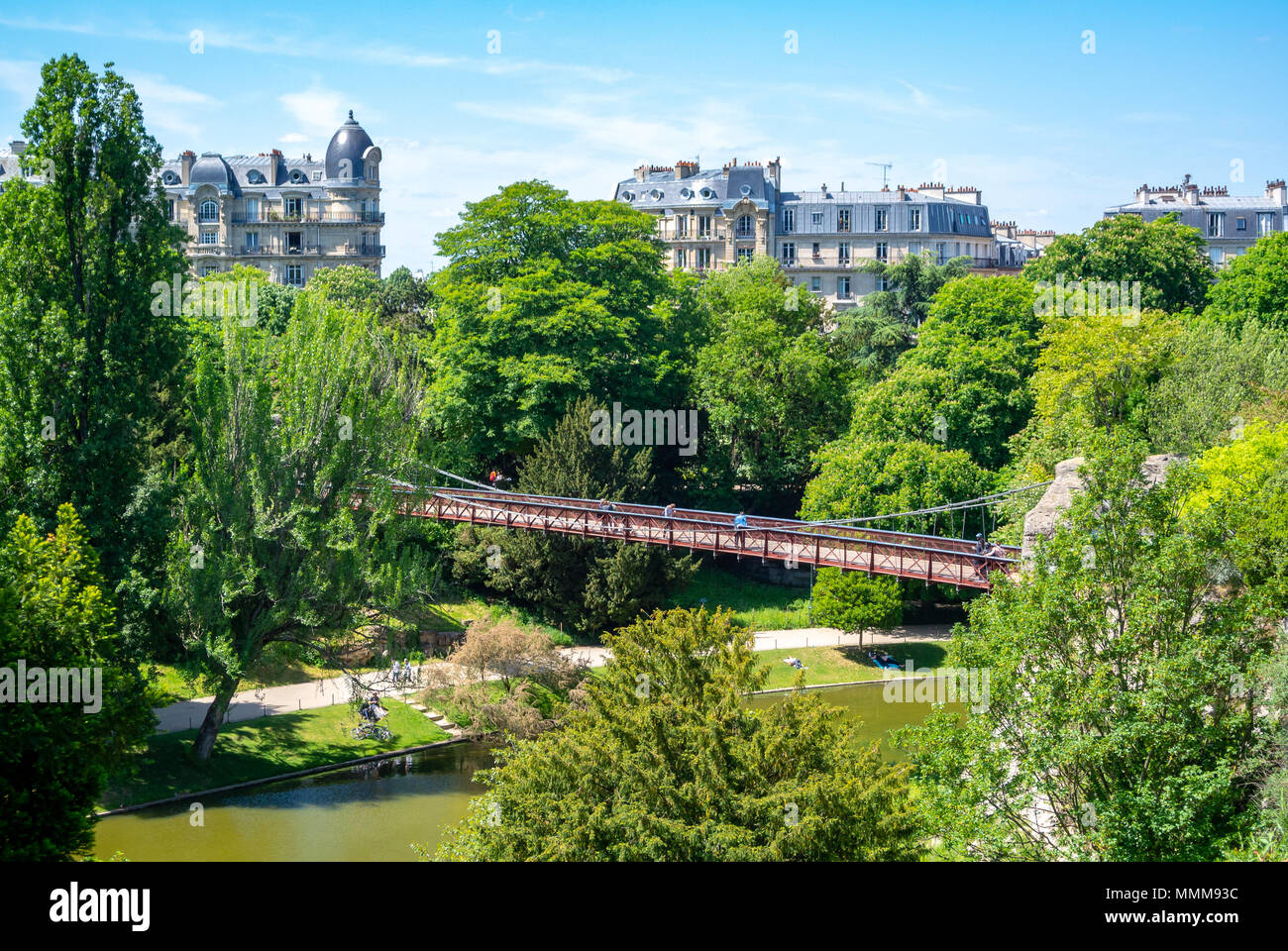 Eine Brücke im Parc des Buttes Chaumont mit Pariser Haussmann Architektur, Paris, Frankreich Stockfoto