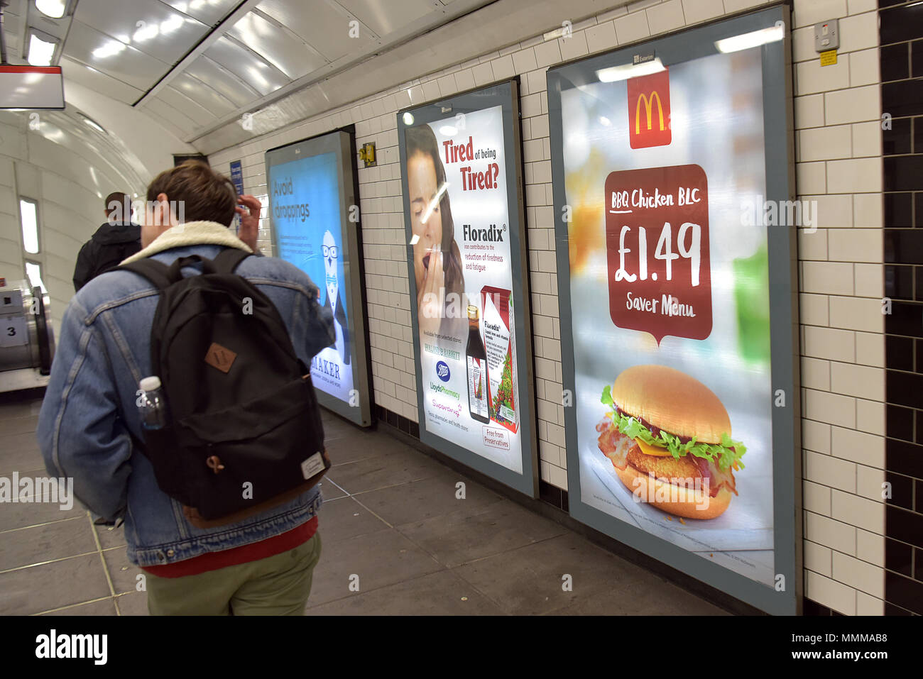 Menschen gehen vorbei Werbetafeln Förderung McDonalds BBQ Chicken Burger in der Notting Hill U-Bahn Station im Zentrum von London. Junk Food ad Stockfoto