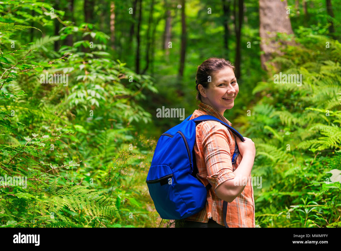 Glückliche Frau mit einem Rucksack durch den Park schlendern Stockfoto