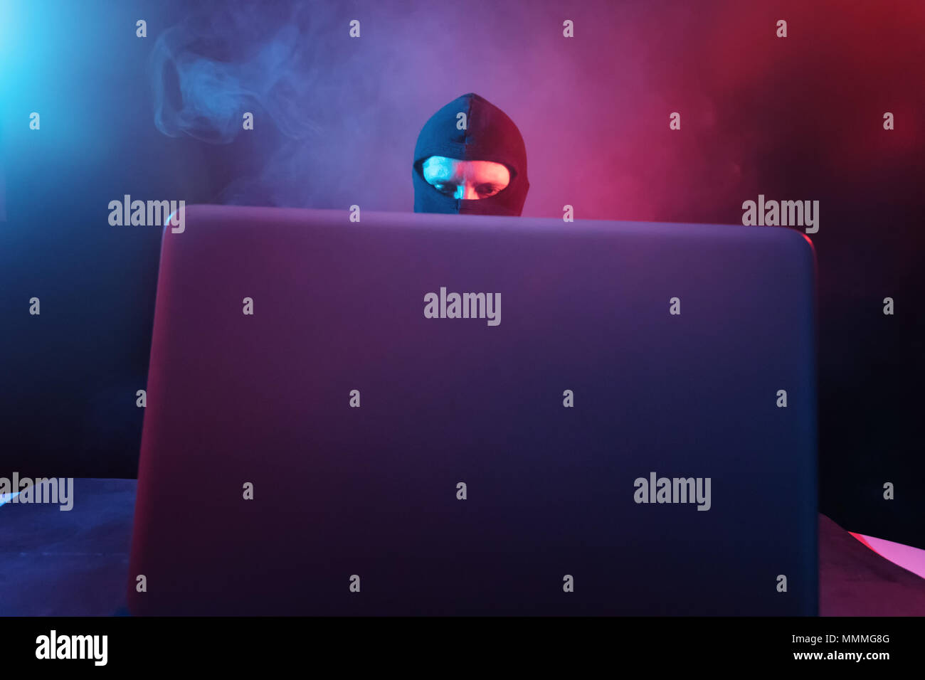 Wütend Computerhacker in Anzug stehlen Daten vom Laptop durch rote und blaue Licht beleuchtet Stockfoto