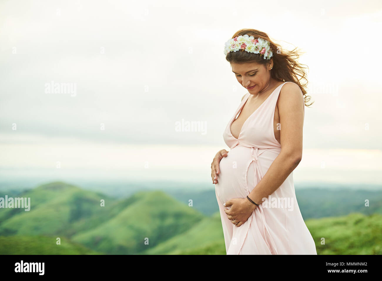 Schwangere Frauen halten ihre Hände auf dem Bauch in den natürlichen Hintergrund Stockfoto