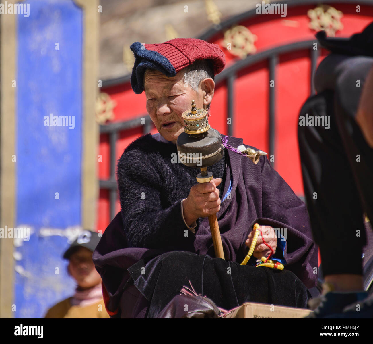 Tibetischen Pilger Spins ein Gebet Rad außerhalb des Heiligen Bakong Schrift Druckmaschine Kloster in Dege, Sichuan, China Stockfoto