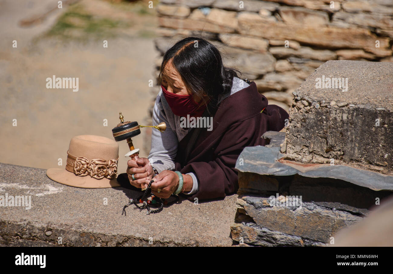 Tibetischen Pilger Spins ein Gebet Rad außerhalb des Heiligen Bakong Schrift Druckmaschine Kloster in Dege, Sichuan, China Stockfoto