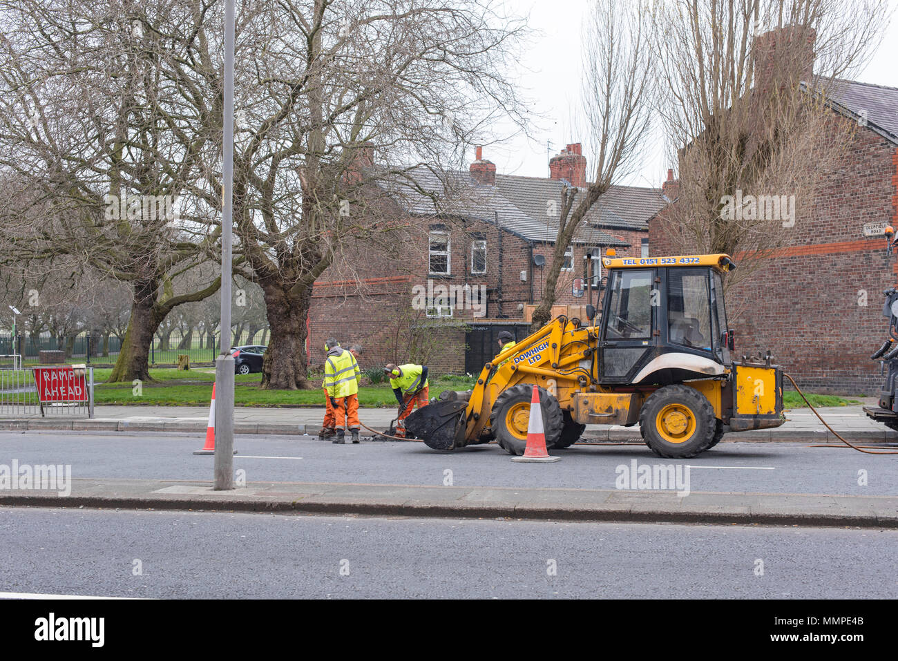 Baustellen Maschinenbauer in Hi-vis Jacken auf Smithdown Road, Liverpool, mit einem gelben Traktor Stockfoto