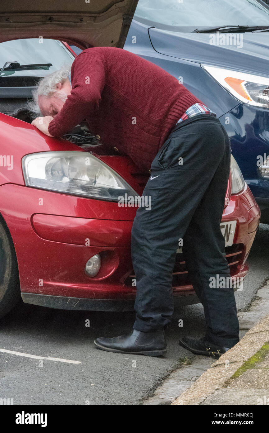 Eine ältere oder im mittleren Alter Gentleman oder Mann sein Auto zur Festsetzung mit der Motorhaube in der oberen Position, um Zugang zum Motor zu erhalten. Kraftfahrer Reparatur Auto Stockfoto