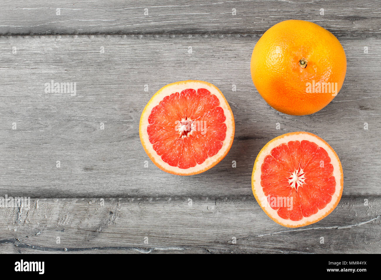 Table Top Aussicht auf rote Grapefruits, auf die Hälfte reduziert, auf grau Holz Schreibtisch platziert. Stockfoto
