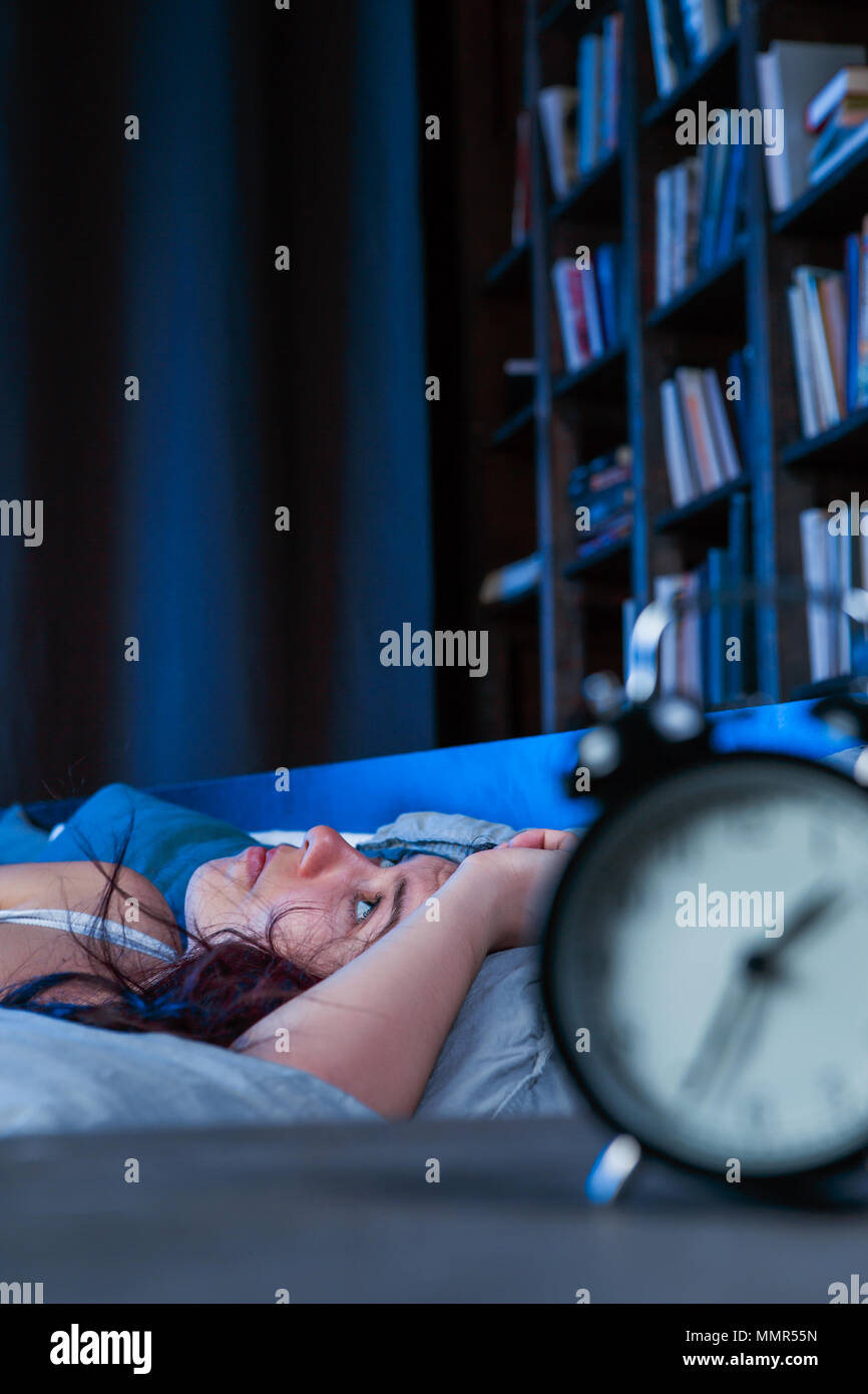 Bild der unglückliche Frau mit Schlaflosigkeit liegend auf Bett neben Wecker in der Nacht Stockfoto