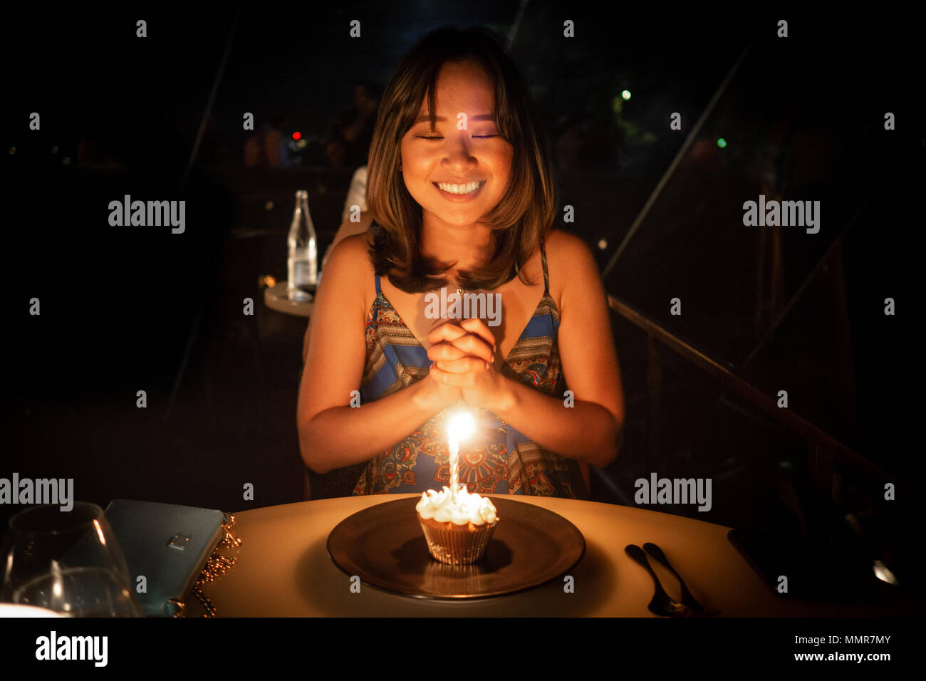 Junge Frau ihren Geburtstag feiern und Wünschen bei einem Abendessen in einem schönen Restaurant Stockfoto