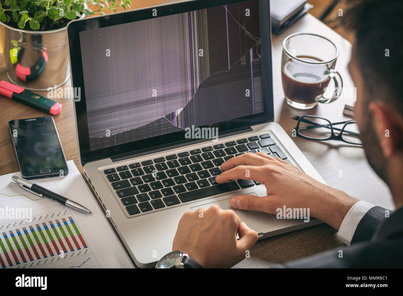 Mann bei der Arbeit mit einem defekten Laptop auf Office Business Hintergrund Stockfoto