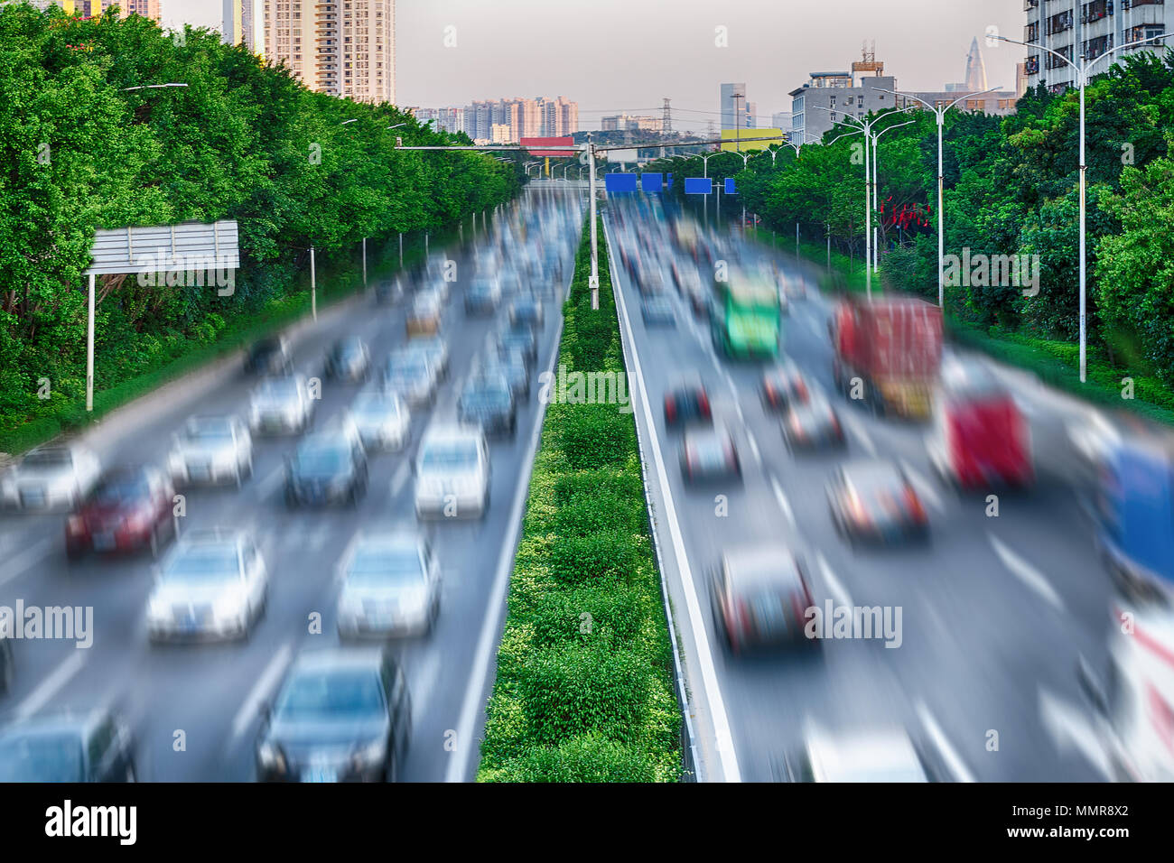 Konzept der Wechselwirkung zwischen Natur und Technik - grüne Bäume und grüne Linie entlang einer befahrenen Straße Umwelt schützen. Autos sind auf der Autobahn. Stockfoto