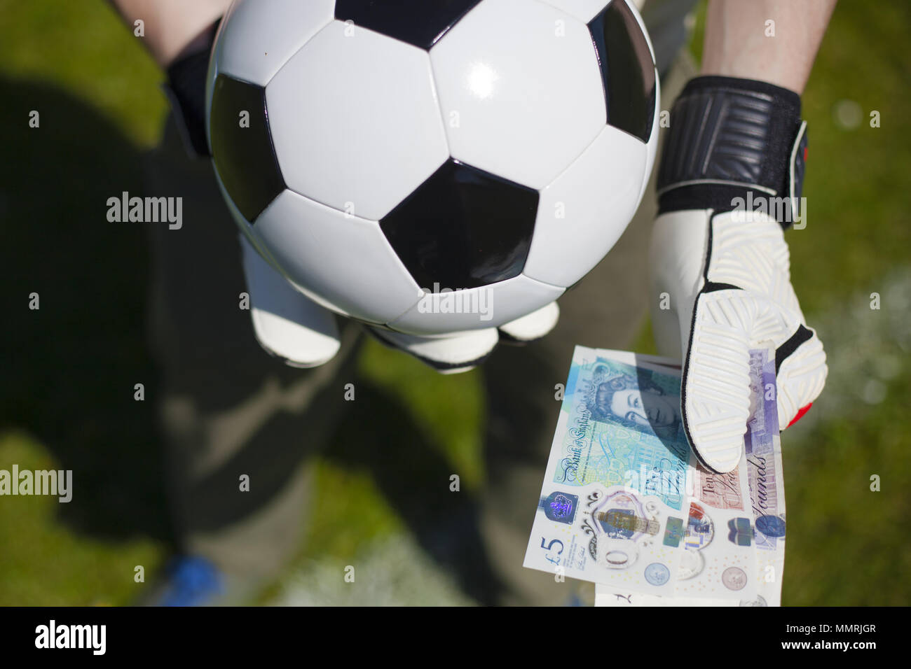 Einen Fußball gegen eine Reihe von Noten, die durch ein Fußball-Spieler gehalten Stockfoto