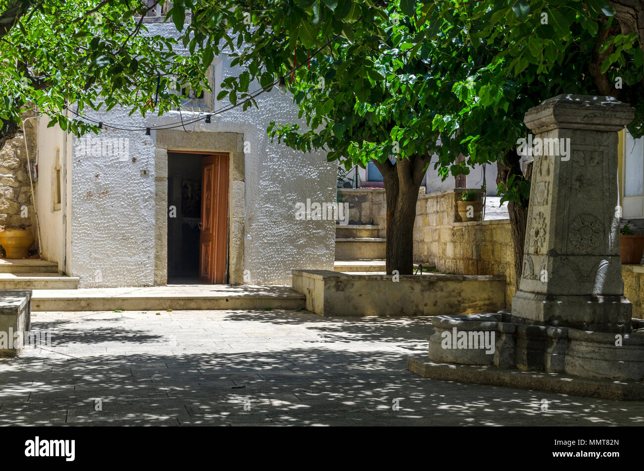 Chersonissos, Kreta/Griechenland. Die "Heilig-Kreuz-Kapelle" in Archanes Village. Stein Brunnen im Innenhof Stockfoto