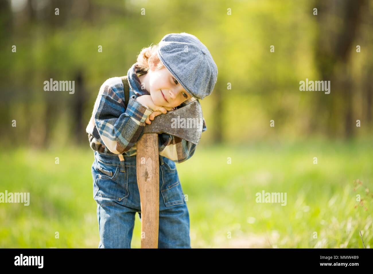 Kleine kaukasischen Jungen in Hut posiert mit großen Ax. Portrait von kleinen Holzfäller Stockfoto