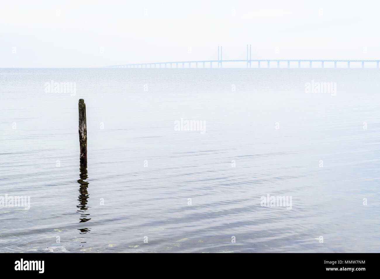 Kalgshamn, Schweden - Liegeplatz pole Allein im Meer an einer ruhigen und nebliger Tag. Die Øresund-Brücke ist in der fernen Nebel sichtbar. Stockfoto