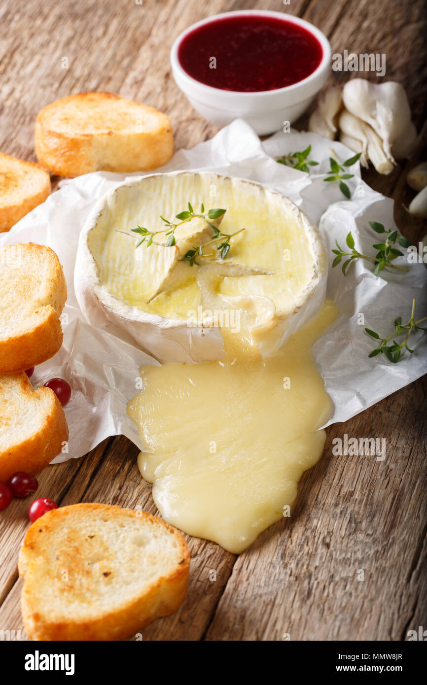 Köstliche Gebackene Camembert mit Thymian und Knoblauch ist mit Toast und Preiselbeersoße schließen serviert - auf den Tisch. Vertikale Stockfoto