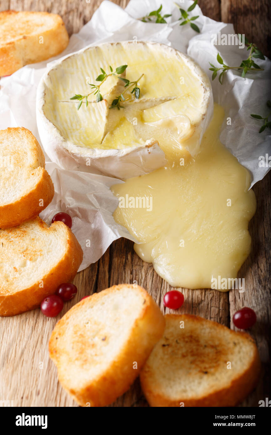 Gebackener Camembert mit Thymian und Knoblauch mit geröstetem Brot in der Nähe serviert - auf den Tisch. Vertikale Stockfoto