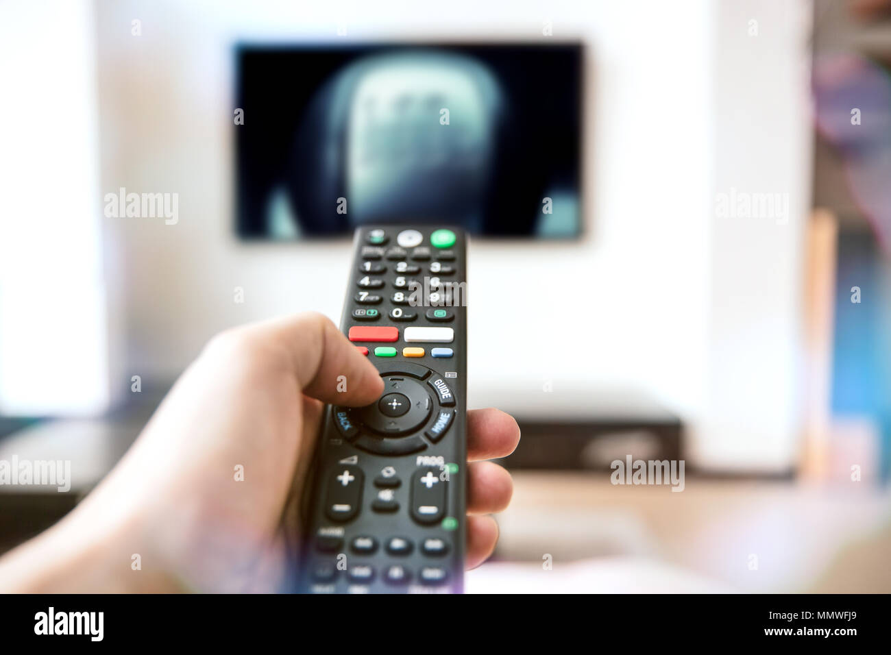 Die menschliche Hand hält eine Fernbedienung für ein modernes Fernsehen Stockfoto