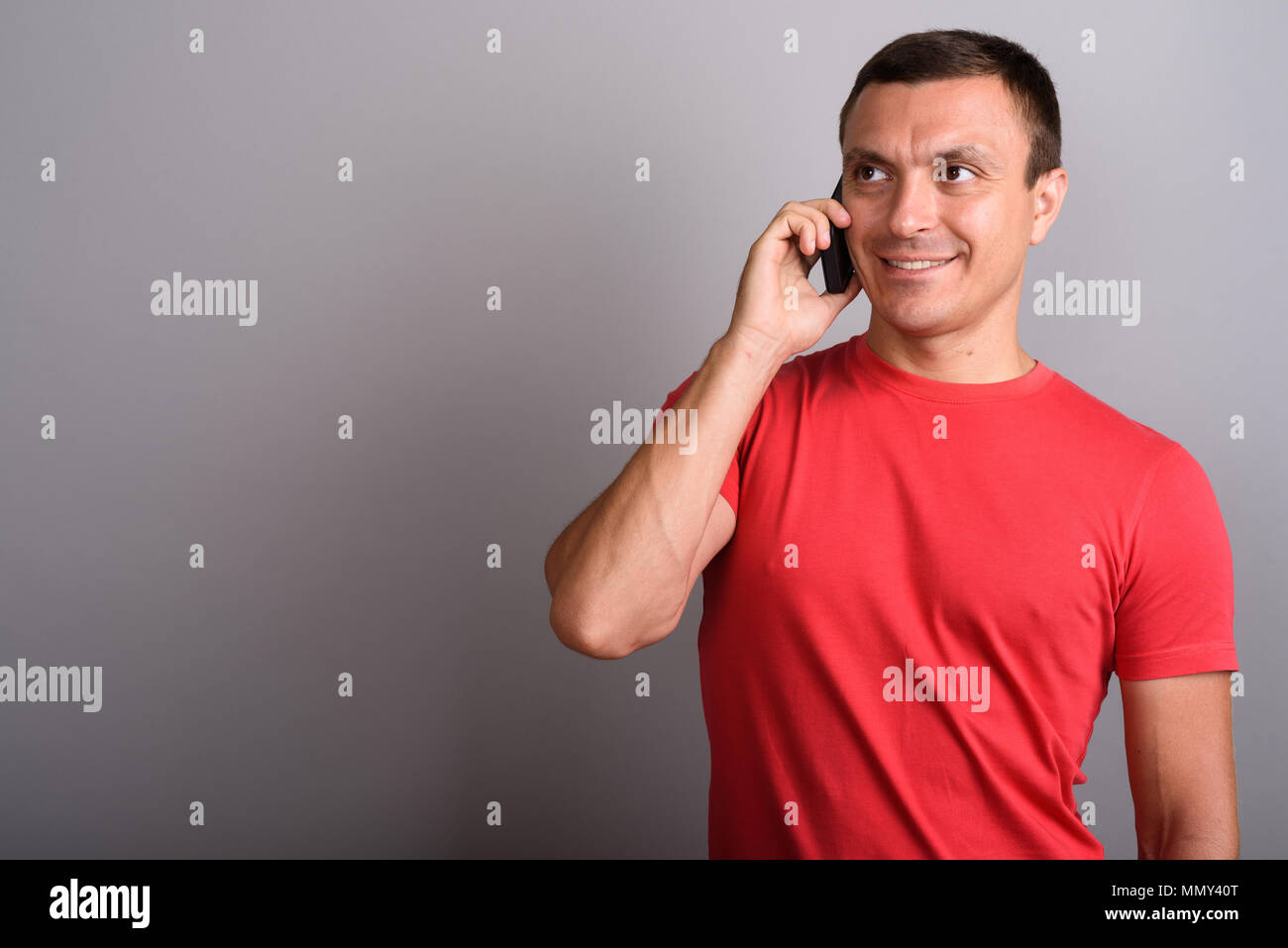 Mann mit roten Hemd, bei der Verwendung von Mobile phone gegen Grau zurück Stockfoto