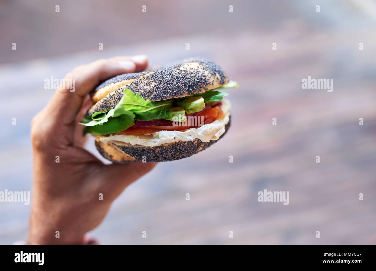 Mann mit einem leckeren Frischkäse und Lachs Bagel Stockfoto