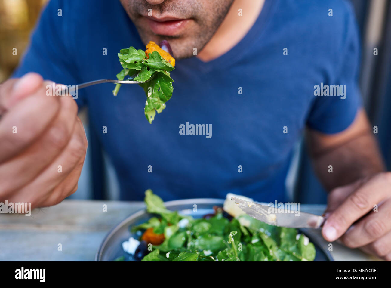Junger Mann essen eine Gabel voll mit leckeren Salat Stockfoto
