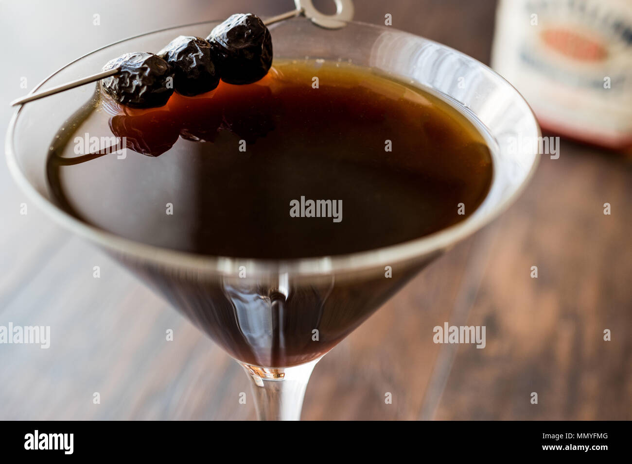 Schwarz Manhattan Cocktail mit Oliven auf dunklen Holz- Oberfläche. Dunkle Konzept. Stockfoto